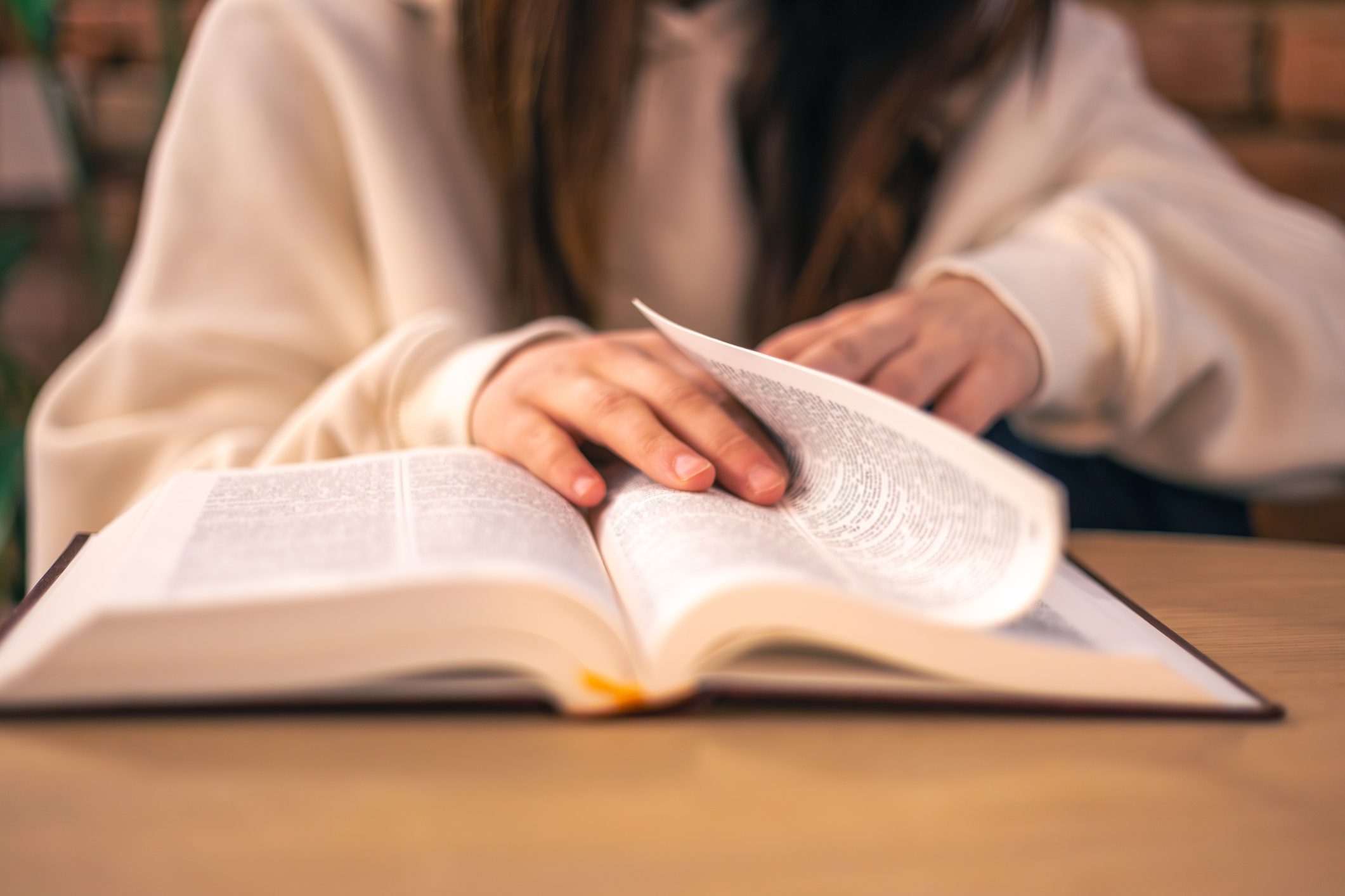 Person reading a book at desk.